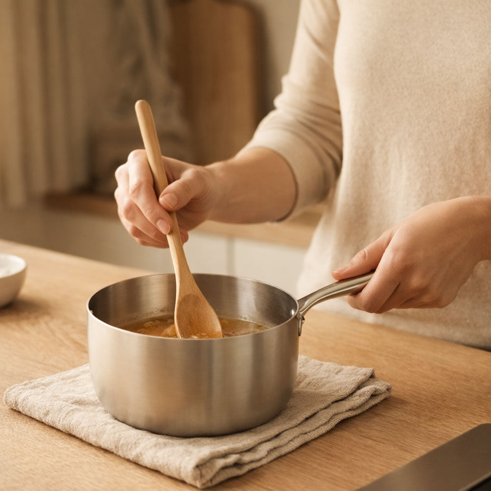 casserole en inox avec de la sauce sur un plan de travail en bois