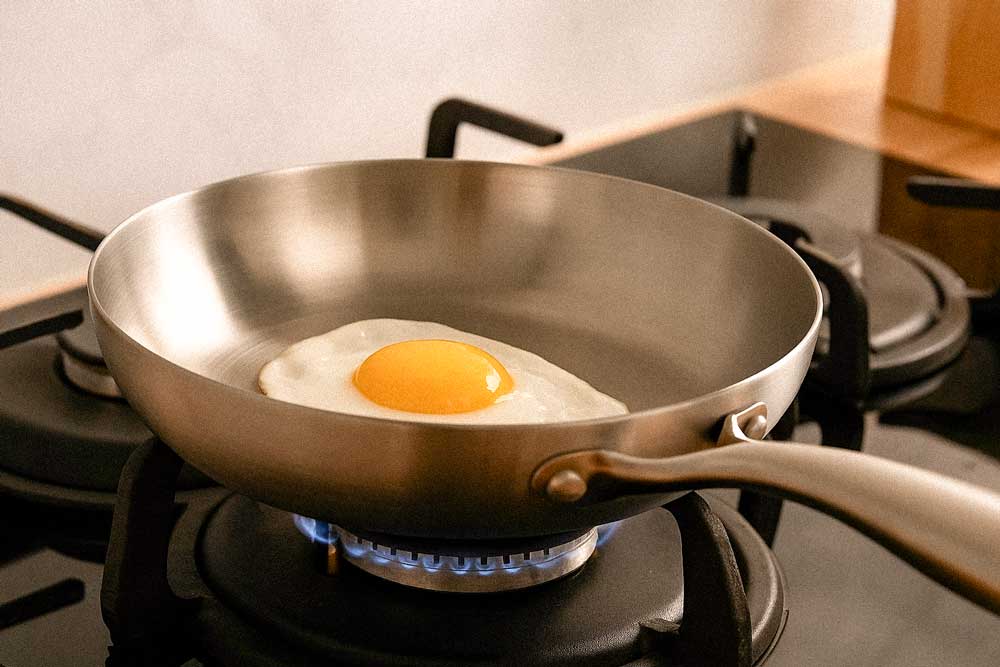 image d'un oeuf au plat en train de cuire dans une poêle en inox